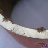 A section through the pipe wall showing an oxide pustule with an underlying corrosion pit